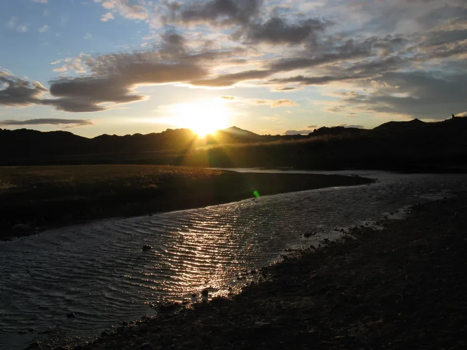Sunset over the river in Mongolia with mountains on the horizon.