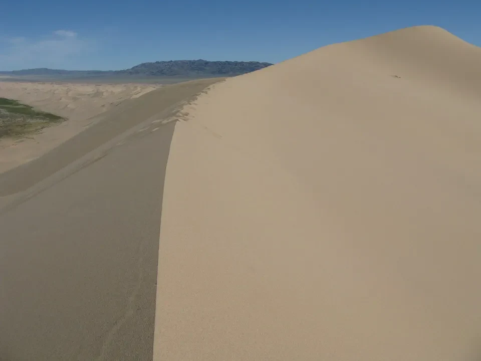 Dune sabbiosa si estende sotto un cielo azzurro in Mongolia.