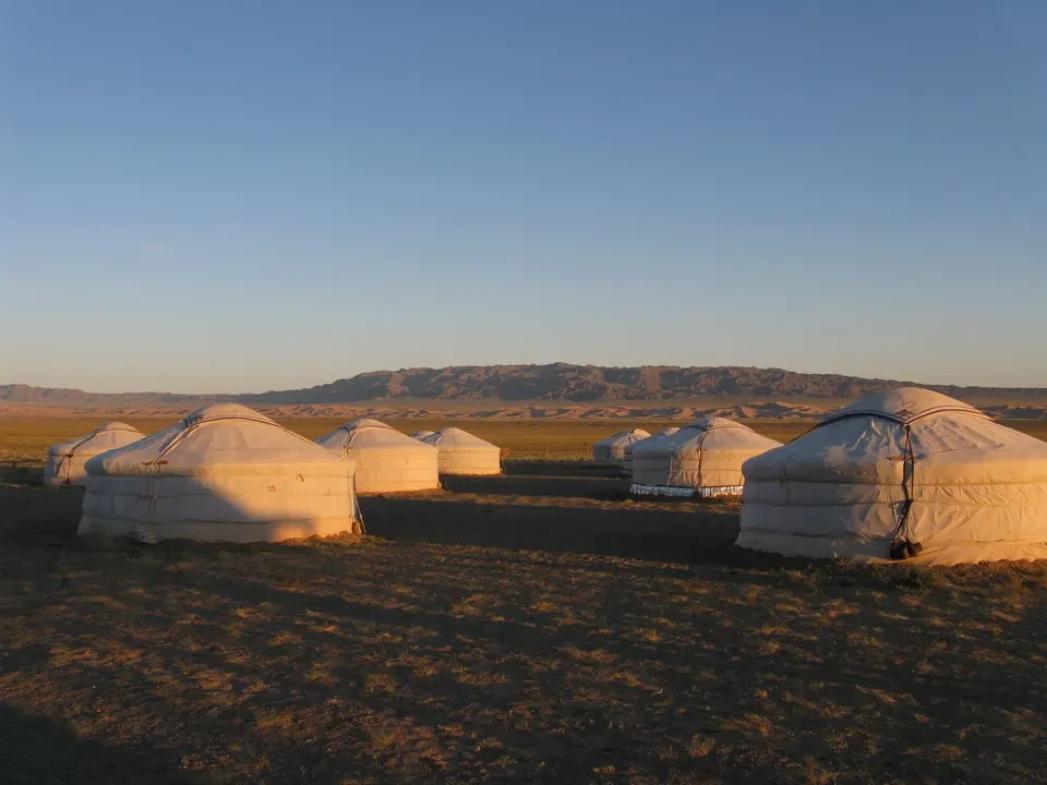 Tende bianche sono disposte su un vasto prato sotto un cielo aperto in Mongolia.