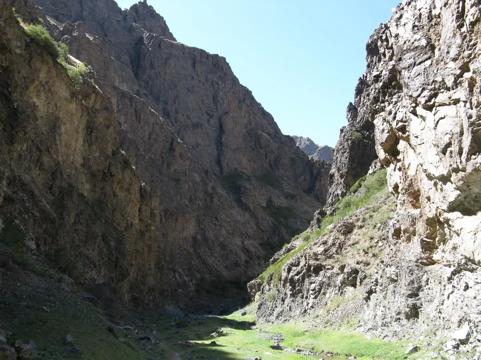Una profonda valle rocciosa e verde si snoda tra montagne ripide.