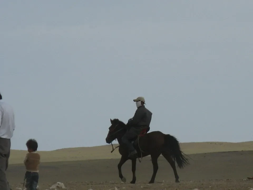 Cavalieri e bambini cavalcano attraverso una vasta distesa di steppe mongole.