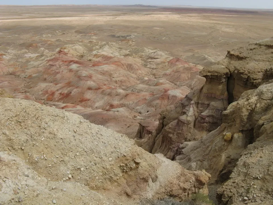 Paesaggio roccioso e arido in Mongolia mostra formazioni geologiche stratificate di colore rosso e ocra.