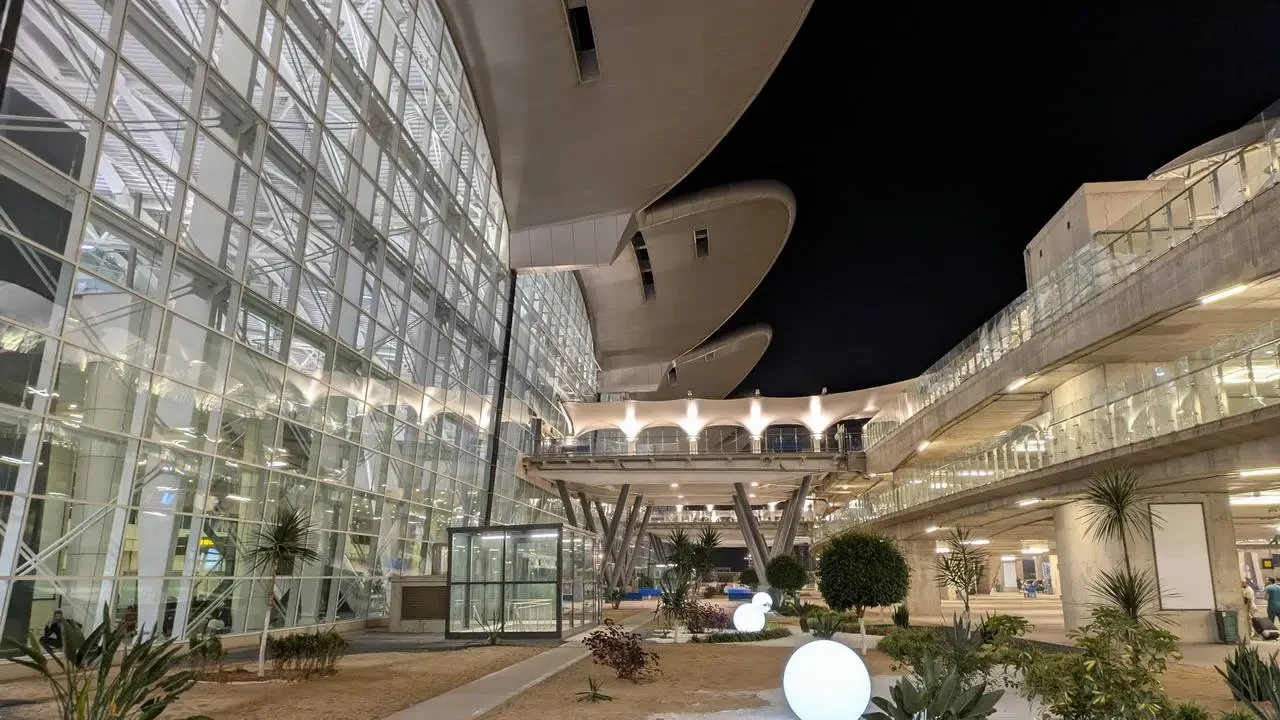 Vista notturna dell'aeroporto di Algeri con architettura moderna e spazi aperti.