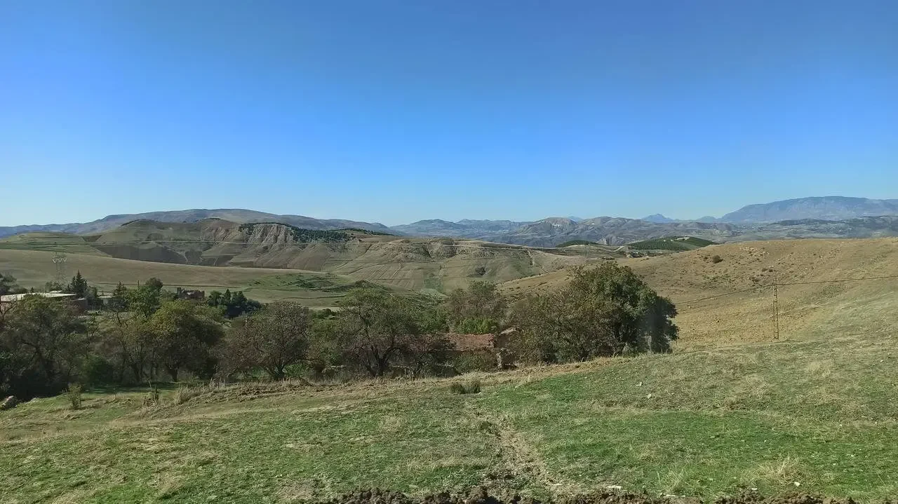 Paesaggio collinare e colline secche in Algeria sotto un cielo azzurro.
