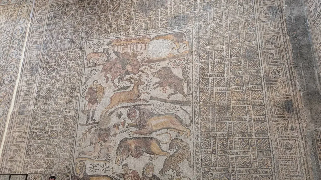 Mosaico decorativo con scene di animali e figure in un edificio storico in Algeria.