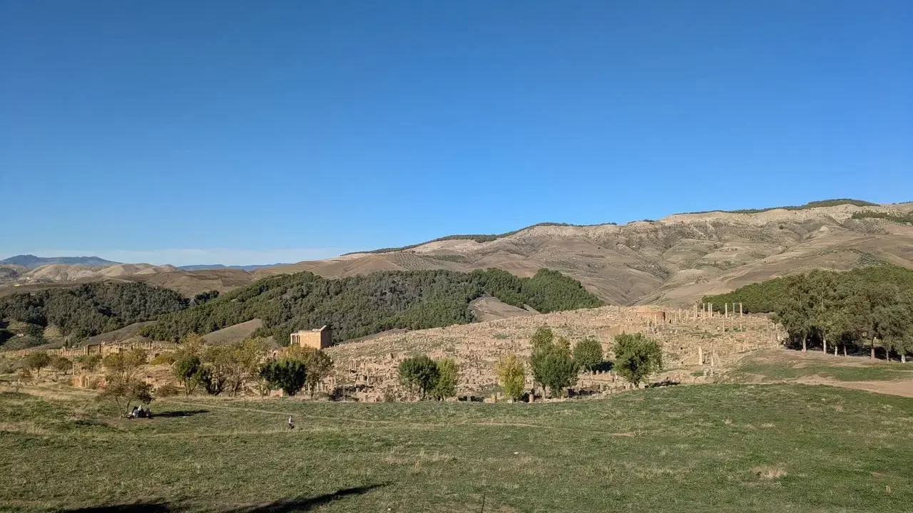 Rovine romane visibili su un paesaggio collinare in Algeria.