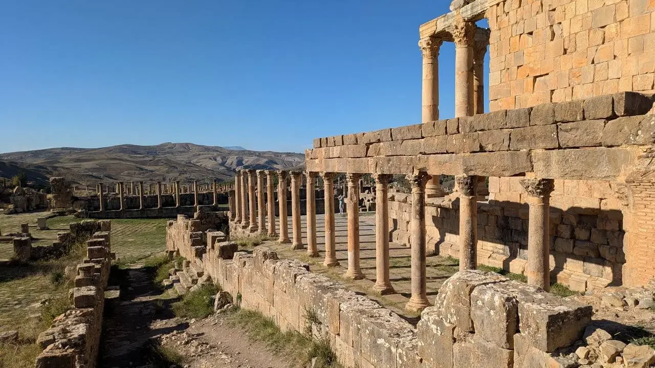 Le rovine di un antico edificio romano con colonne in pietra si estendono sotto un cielo limpido.