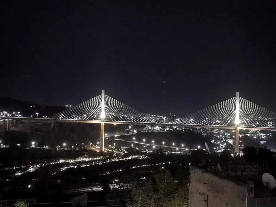 Ponte illuminato di notte sopra un paesaggio urbano in Algeria.