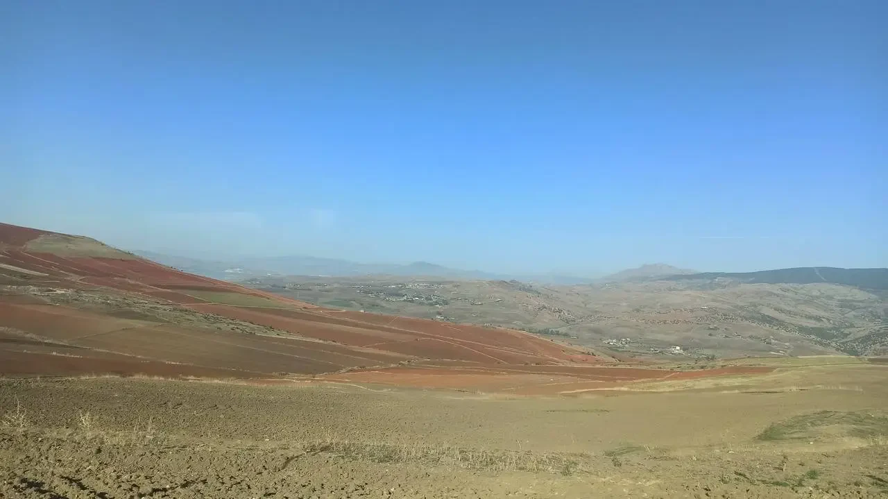 Paesaggio desertico e collinare in Algeria sotto un cielo azzurro.
