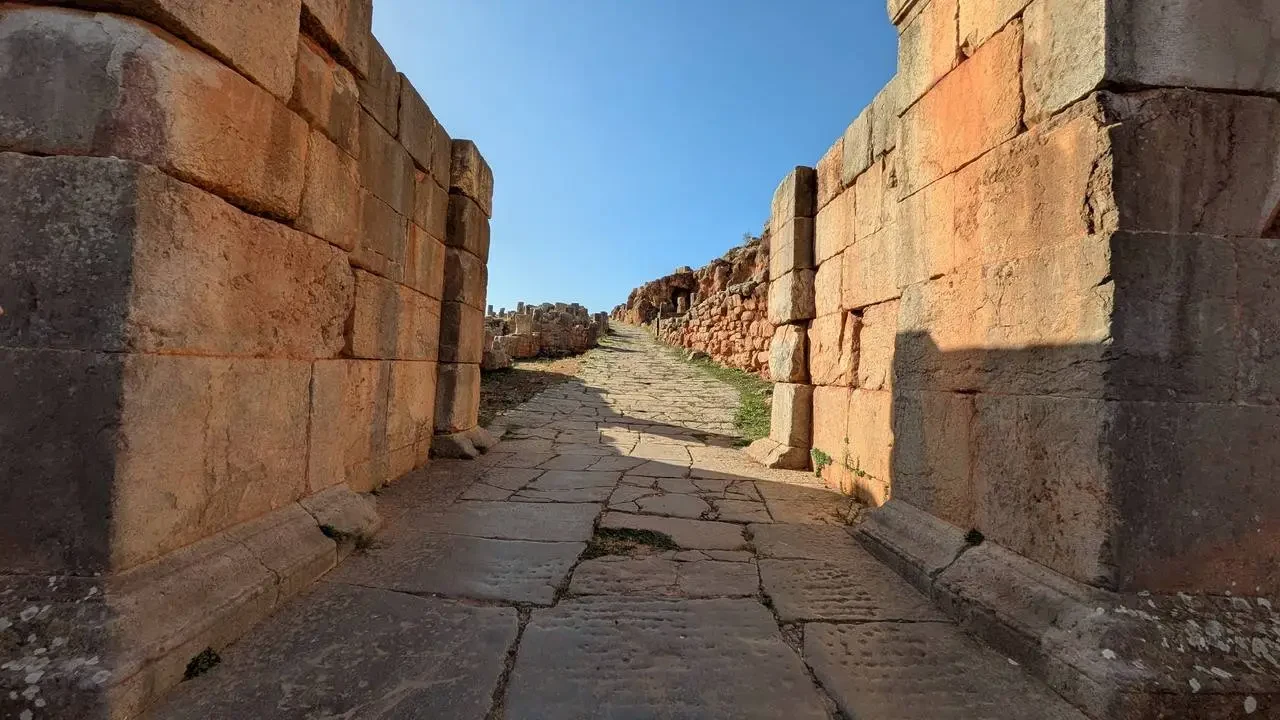 Le rovine di una strada antica in pietra sotto il sole.