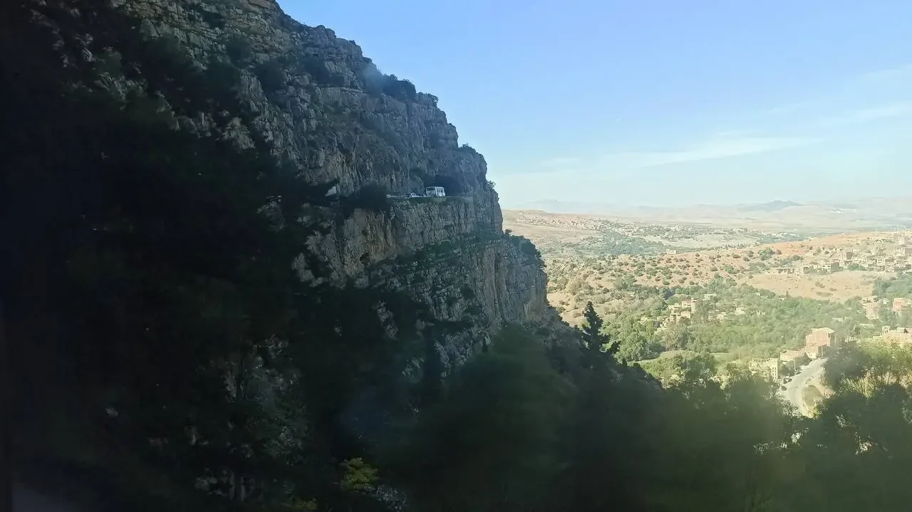 Una scogliera rocciosa domina un vasto paesaggio collinare e arido.