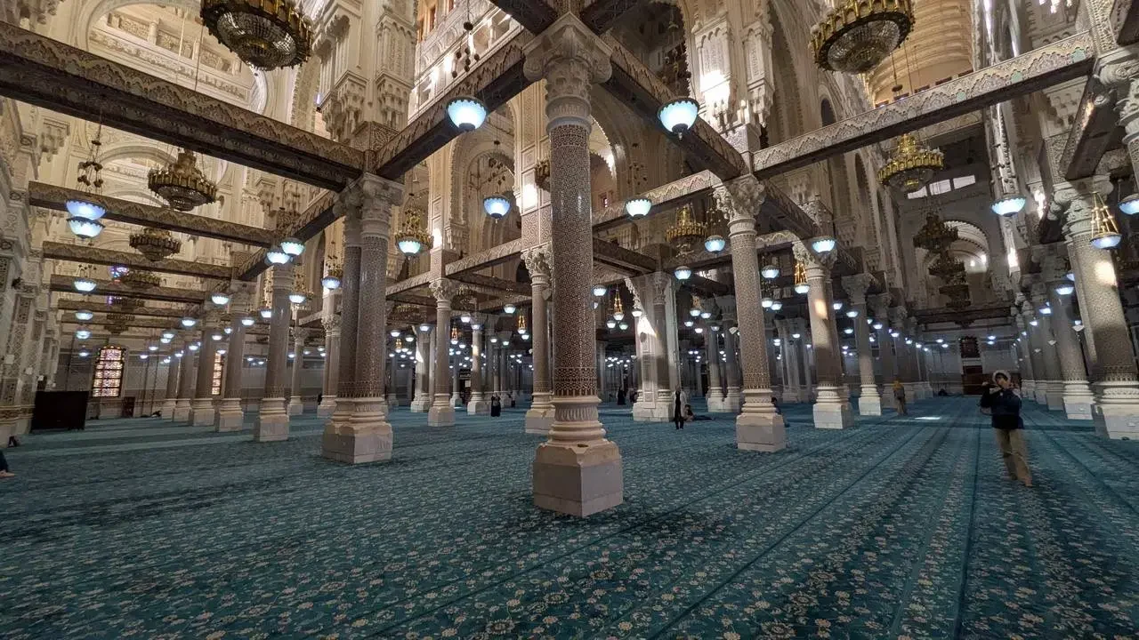 Interno della moschea Emir Abdelkader a Constantine con colonne e tappeto verde.