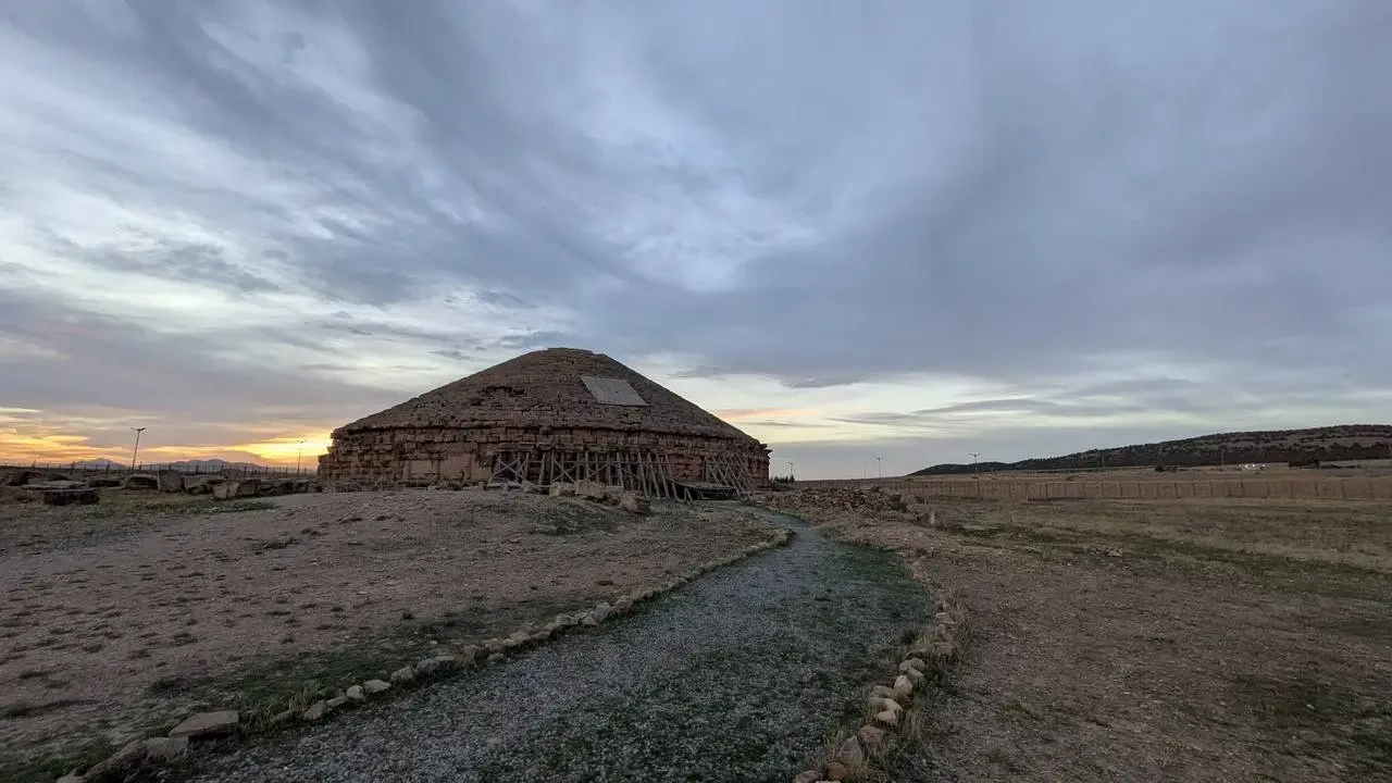 Mausoleo antico in un paesaggio arido dell'Algeria con un sentiero che conduce alla struttura.