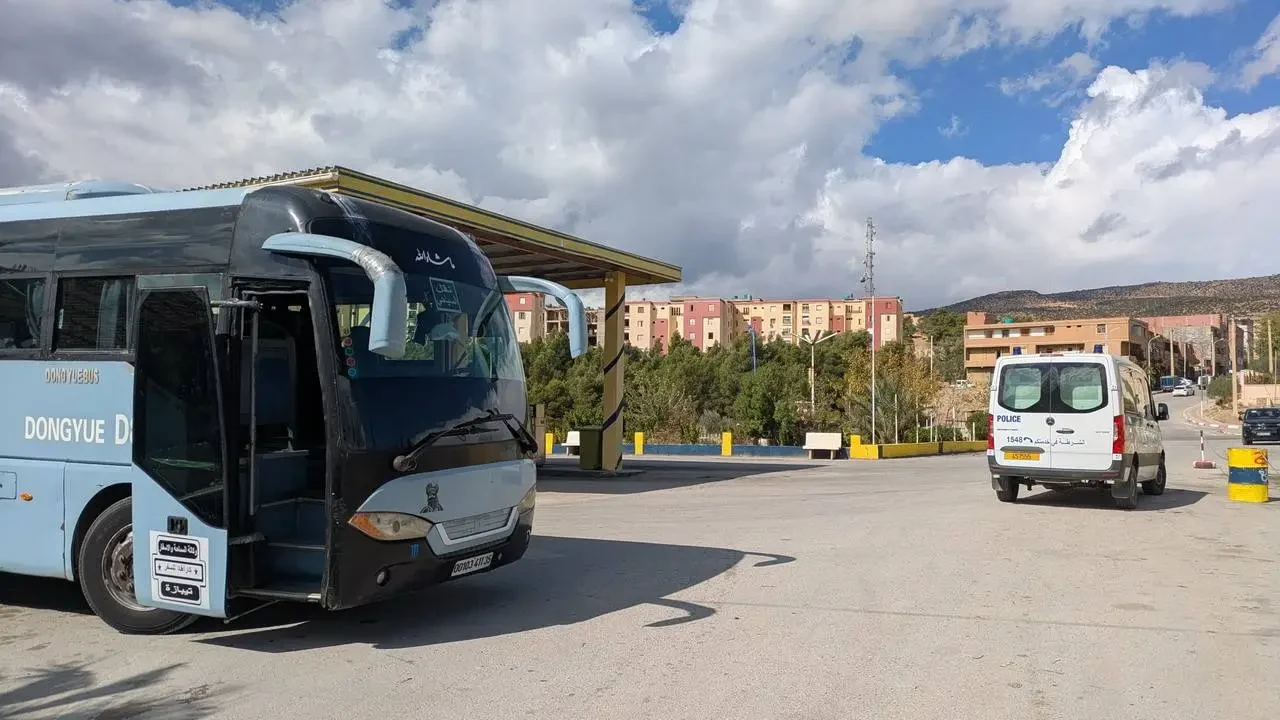 Un autobus si ferma in un piazzale all'aperto con veicoli parcheggiati.