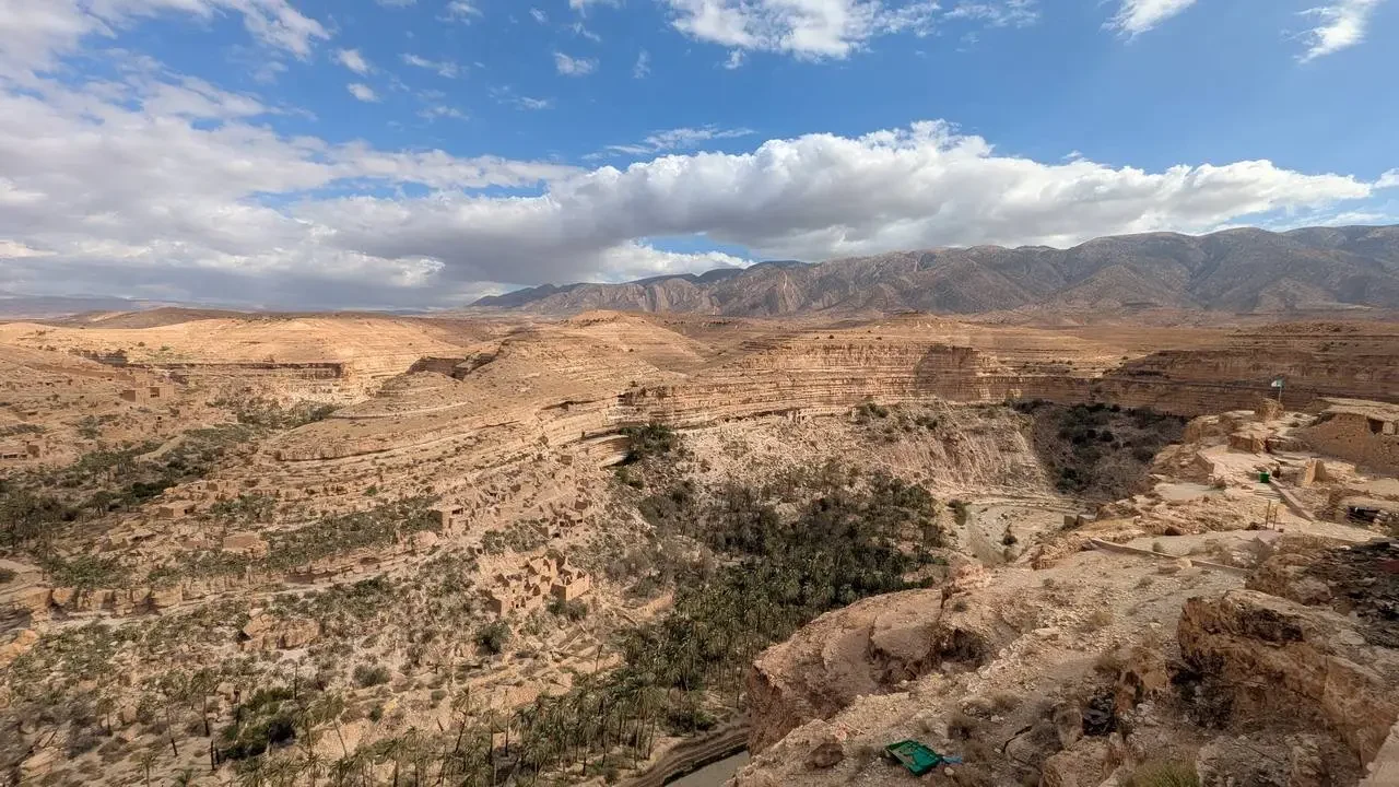 Paesaggio ampio del canyon Ghoufi in Algeria con montagne aride e cielo nuvoloso.
