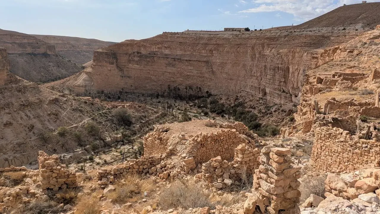 Un profondo canyon arido e roccioso in Algeria mostra antiche rovine di pietra nel paesaggio desertico.