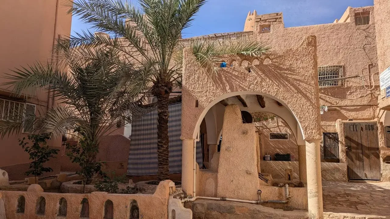 Architettura tradizionale in terra cotta con palme in un paesaggio nordafricano.