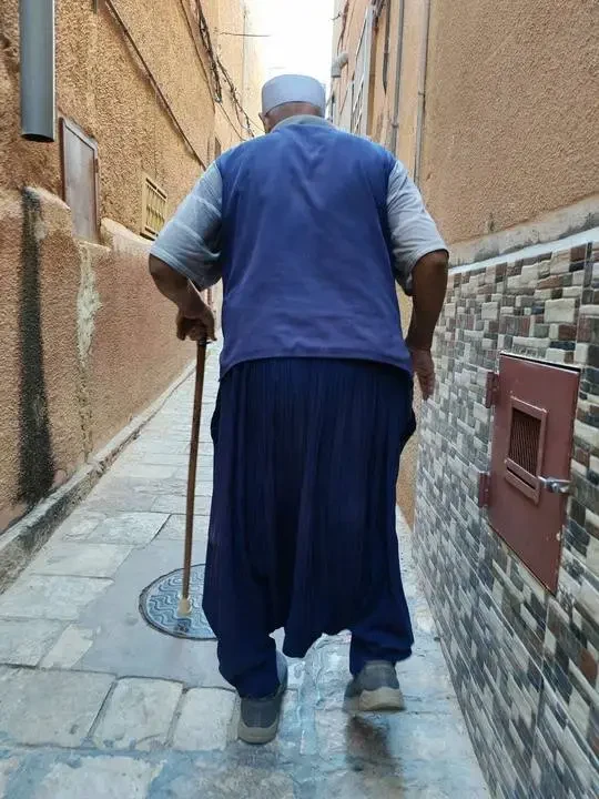 Un uomo indossa abiti tradizionali cammina lungo una strada in Algeria.