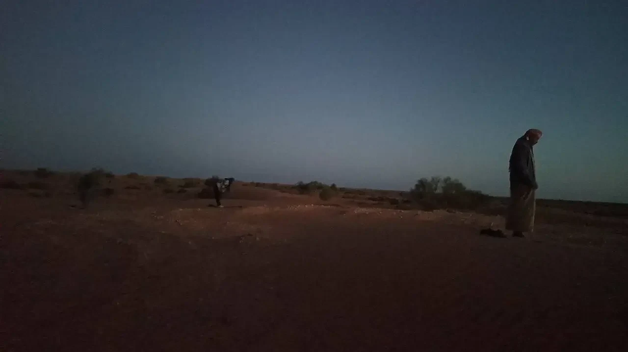 Un uomo si staglia contro il cielo all'alba nel deserto algerino.