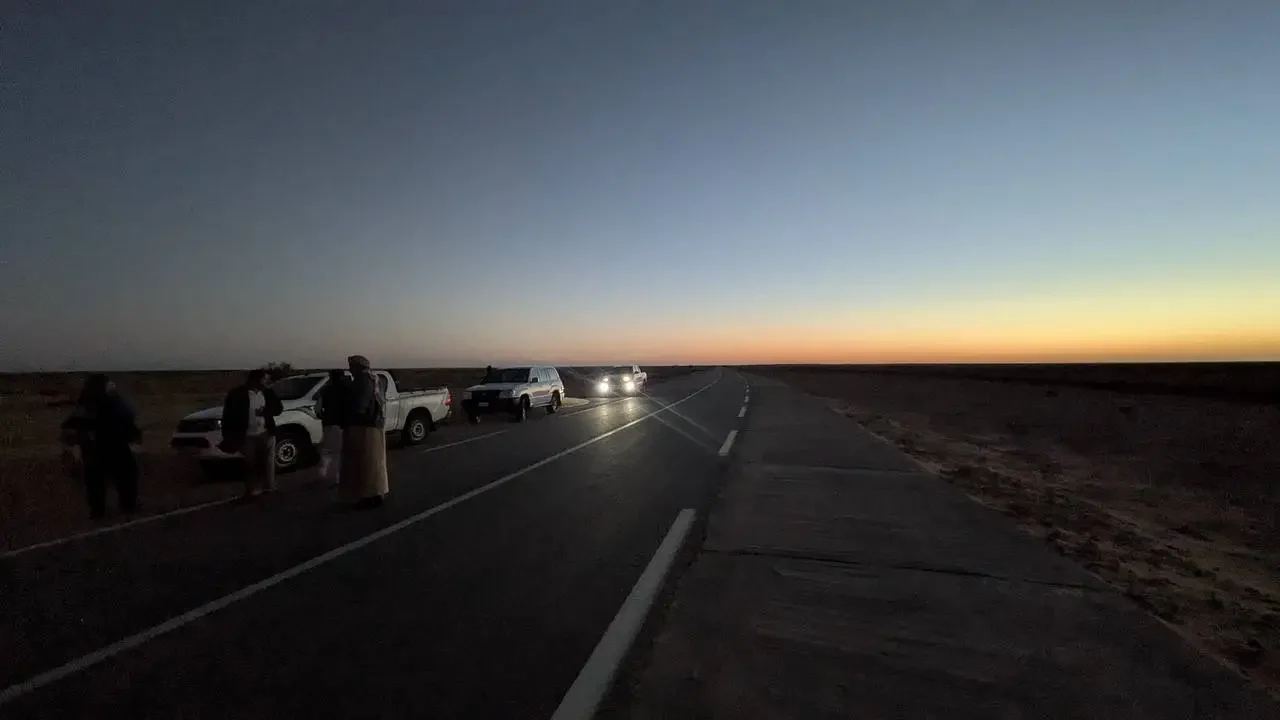 Una lunga strada si estende attraverso un paesaggio arido all'alba in Algeria.