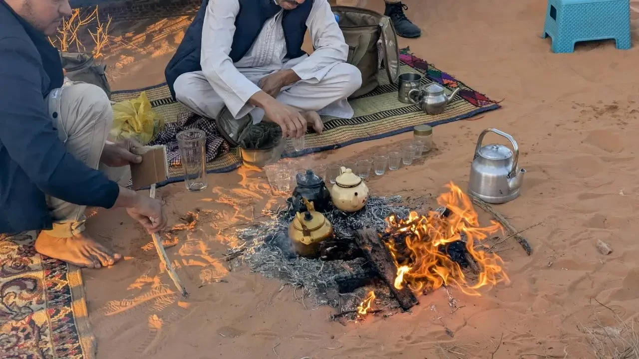 Due uomini preparano un fuoco all'alba nel deserto.