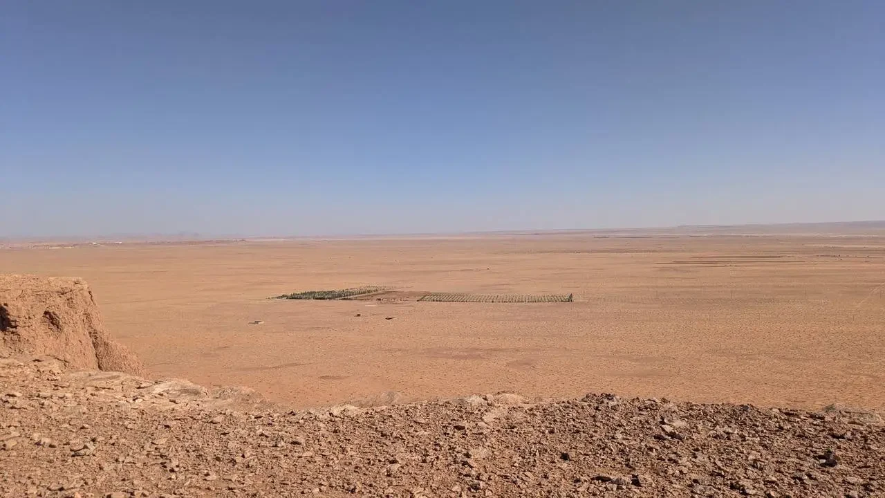 Paesaggio desertico arido con terreno rosso e cielo limpido in Algeria.