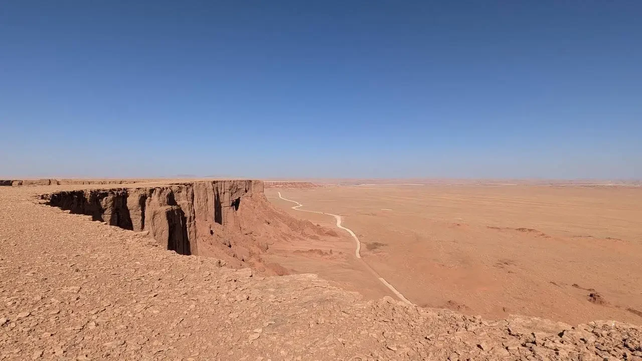 Paesaggio desertico con imponenti scogliere rocciose e una strada sterrata nel deserto algerino.
