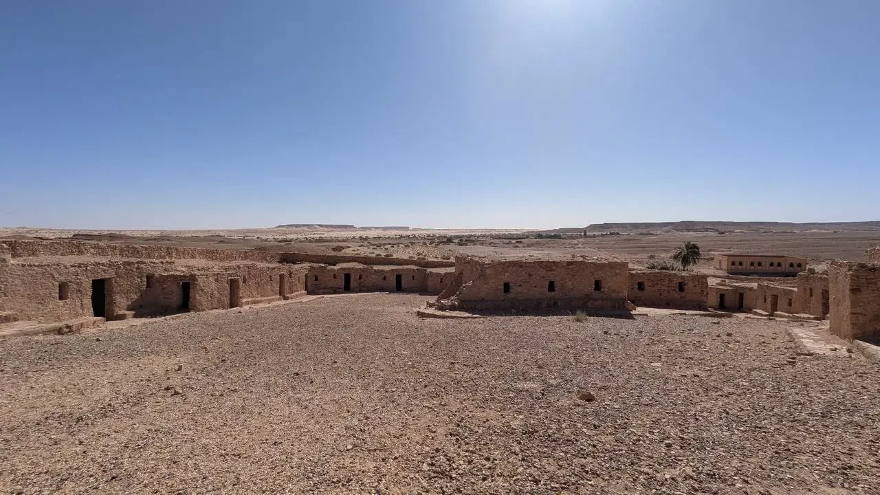 Strutture in mattoni di fango si estendono su un vasto paesaggio desertico algerino.