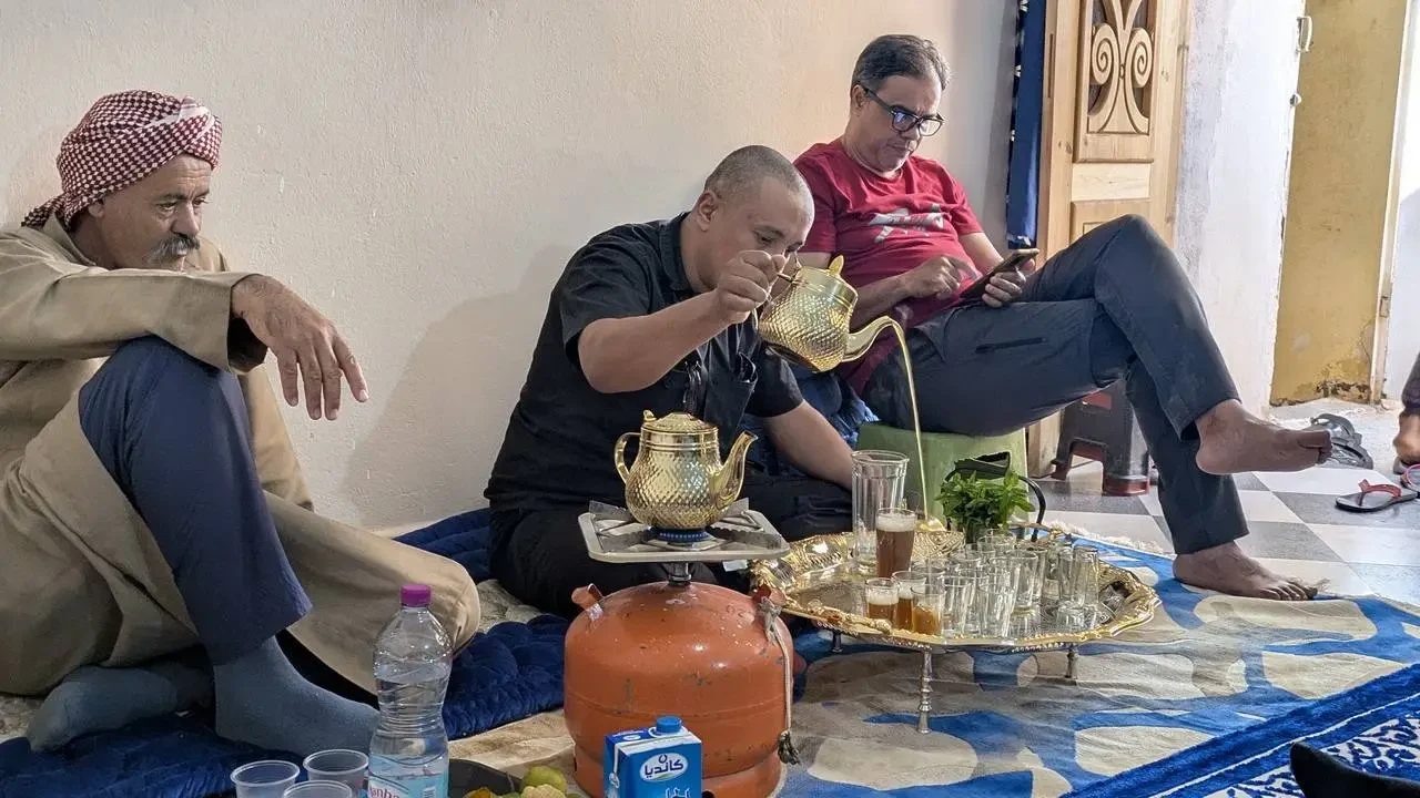 Uomini si godono un pranzo tradizionale in un ambiente interno in Algeria.