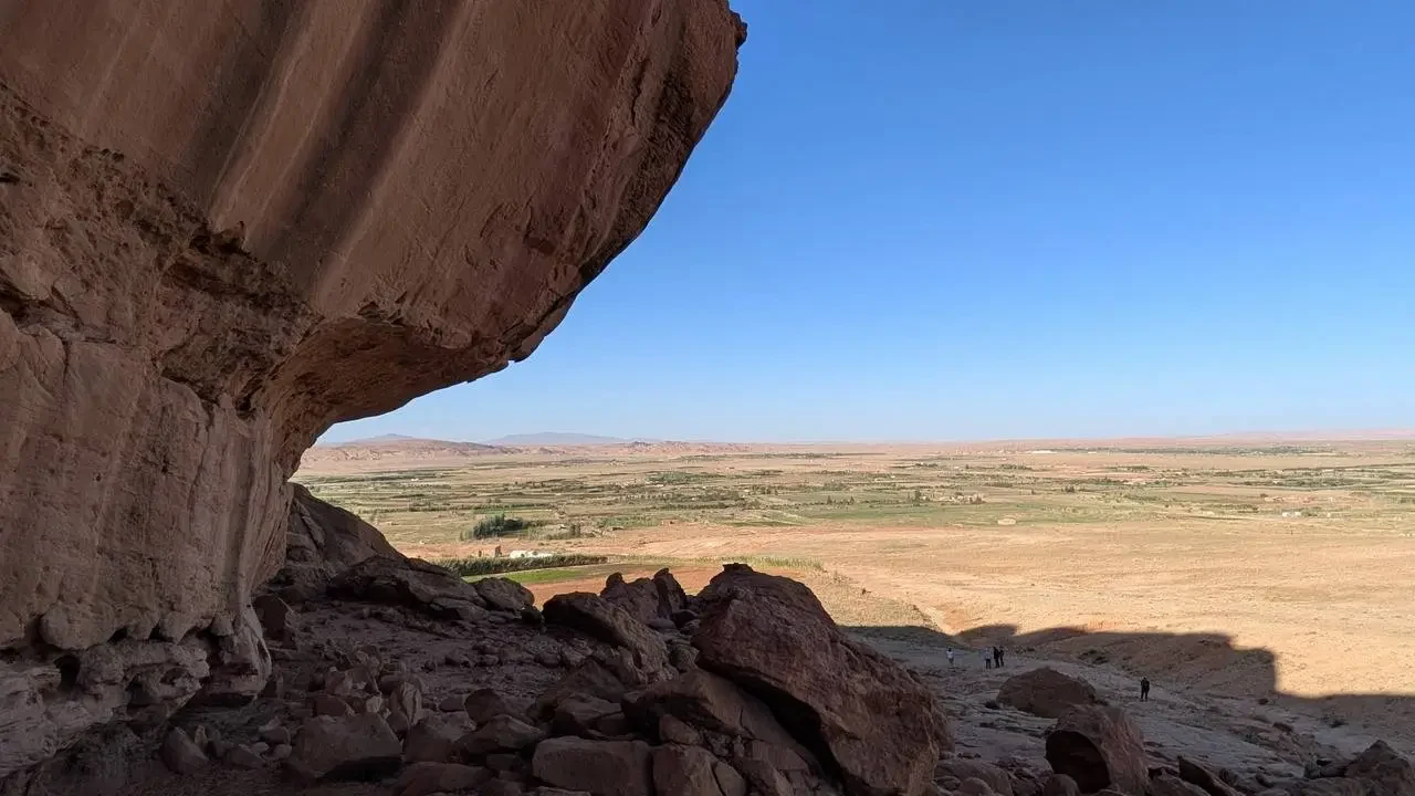 Petroglifi visibili su una formazione rocciosa in Algeria sotto un cielo azzurro.