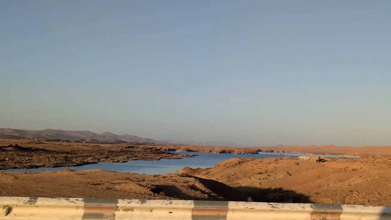 Paesaggio arido e vasto dell'Algeria con terreno secco e colline lontane.