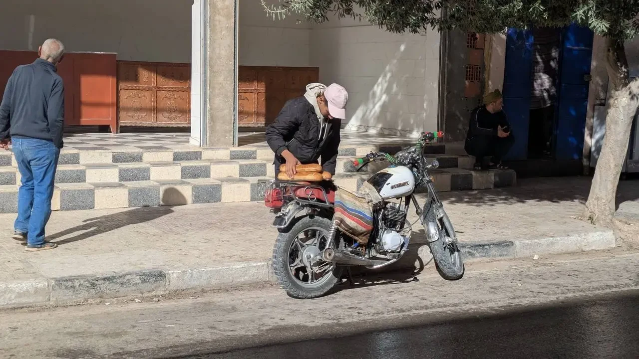 Un uomo e una moto sono presenti davanti a un edificio in Algeria.