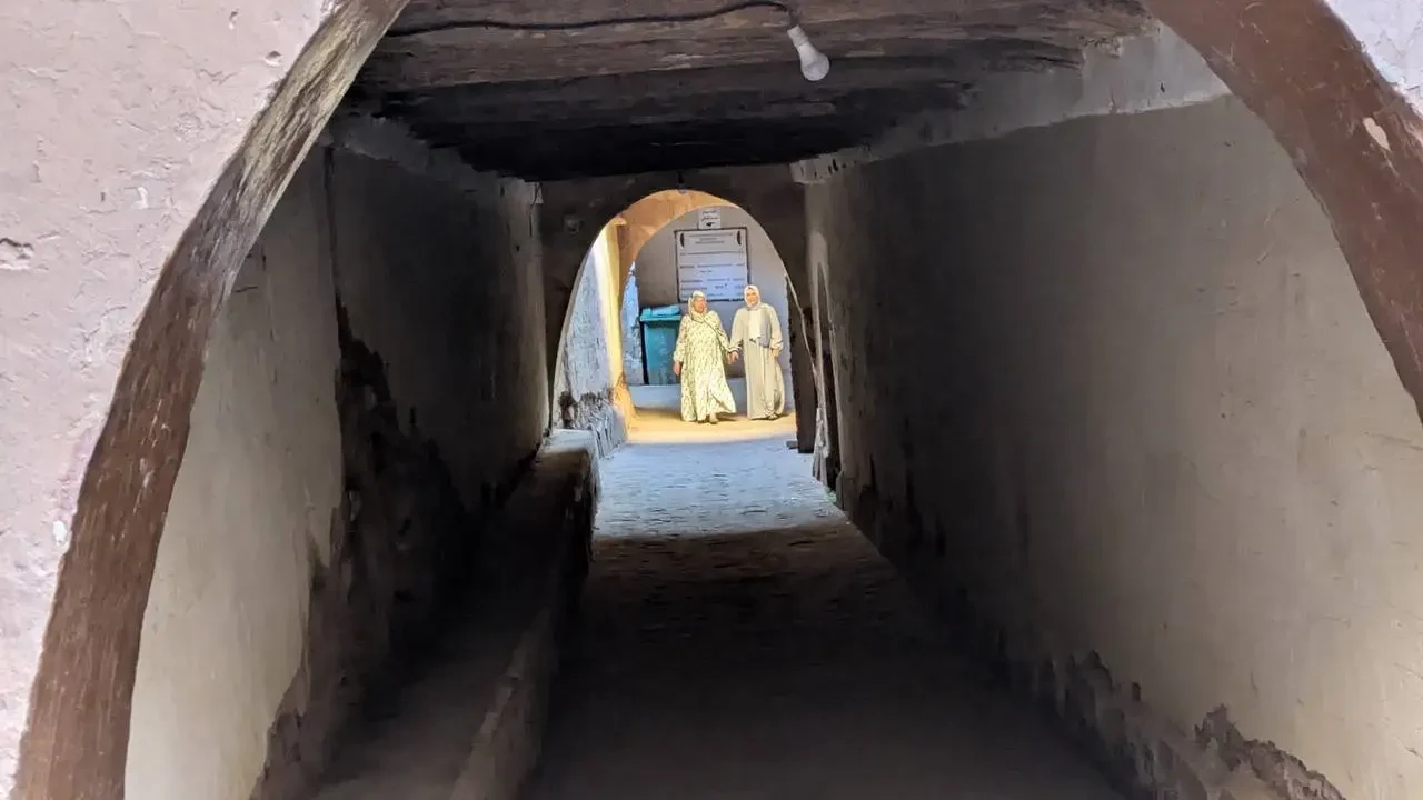 Corridoio stretto ad arco che conduce a due uomini in fondo al passaggio.