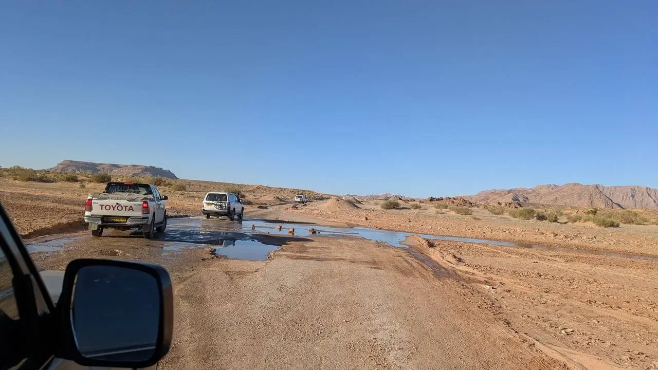 Un veicolo attraversa un tratto di strada sterrata e fangosa nel deserto algerino.