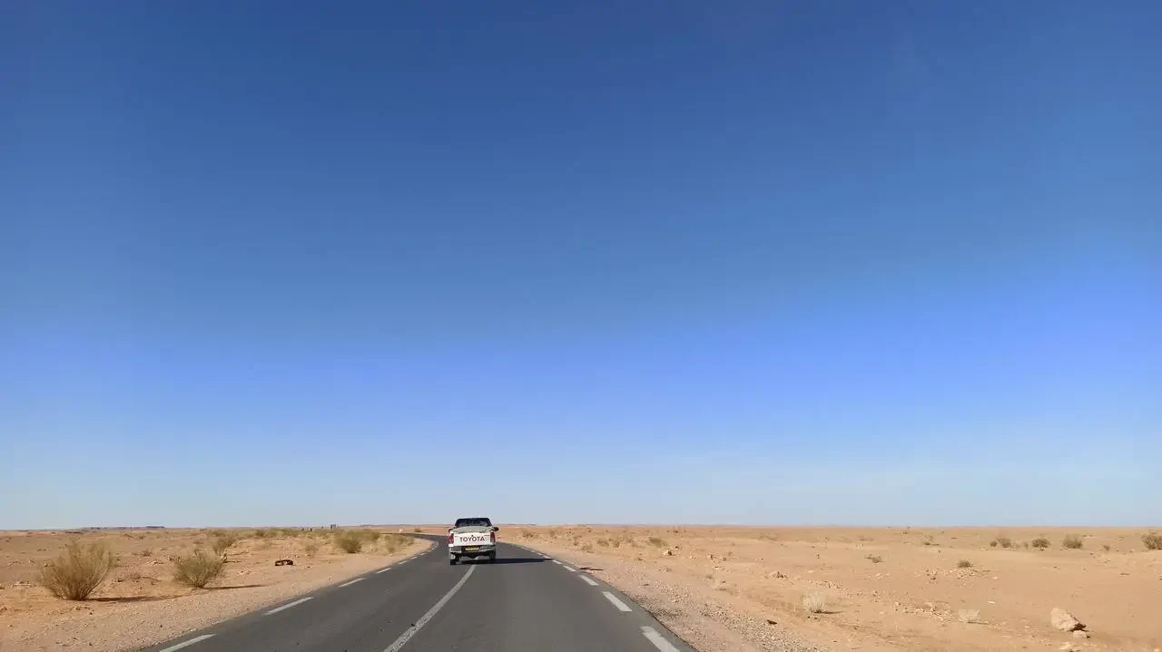 Una strada asfaltata attraversa un paesaggio desertico in Algeria.