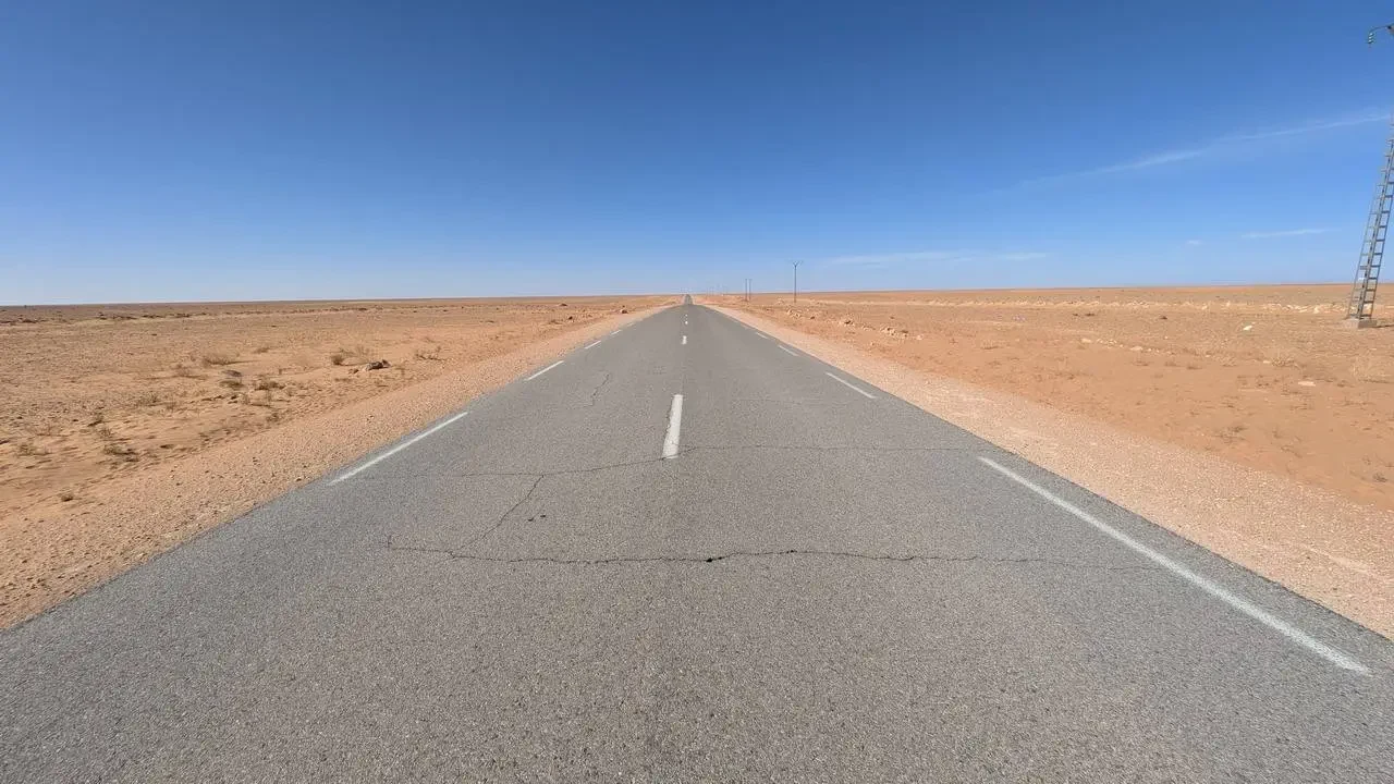 Una strada asfaltata si estende attraverso un paesaggio arido in Algeria.