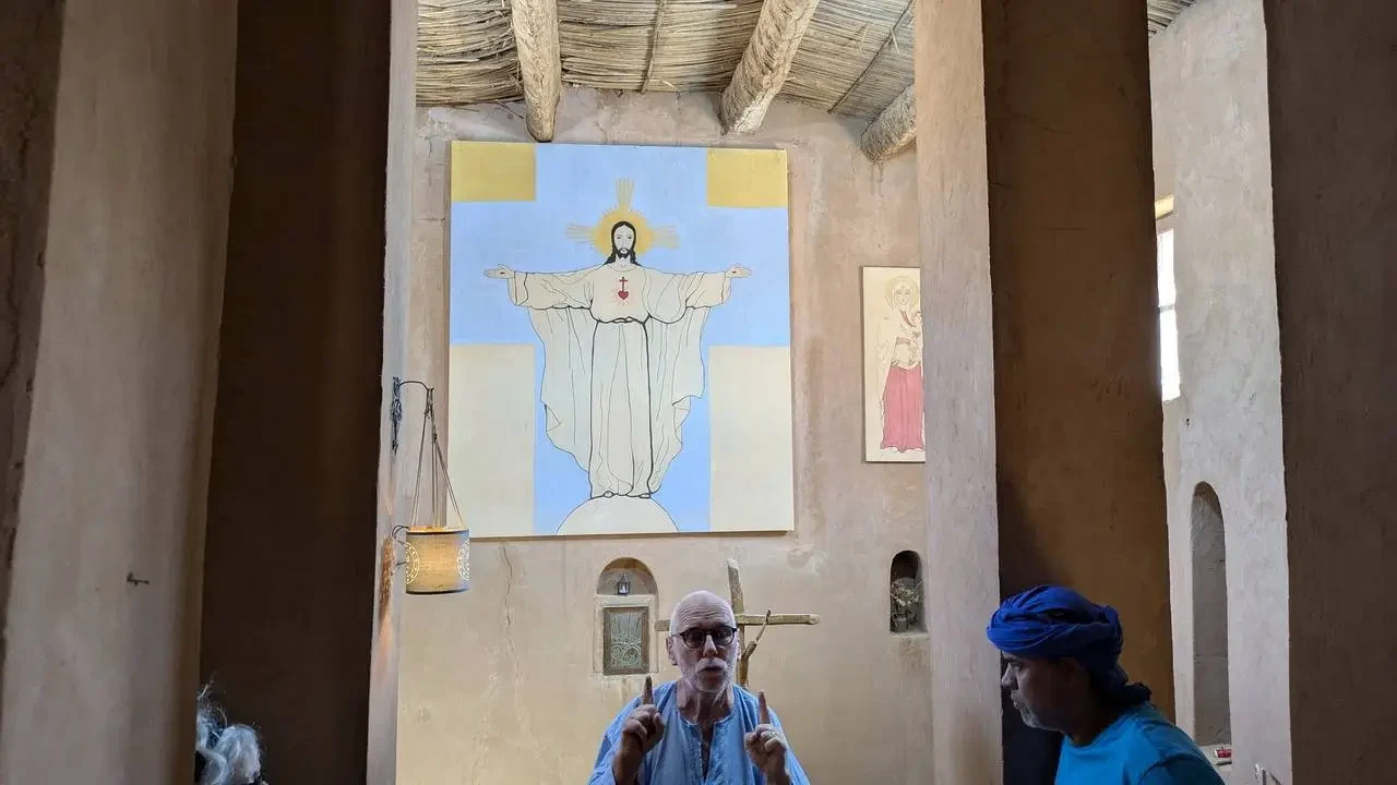 Interno di un edificio religioso in Algeria con affreschi e persone.