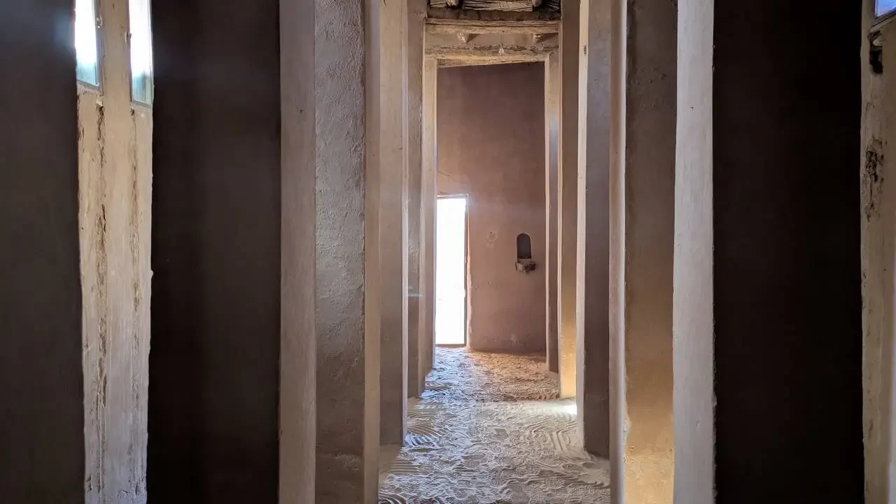 Un corridoio interno con pareti chiare e una pavimentazione ruvida in un edificio in Algeria.