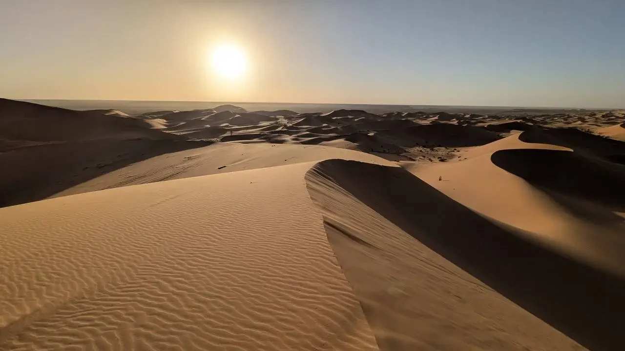 Dune dorate si estendono sotto il sole al tramonto nel deserto algerino.