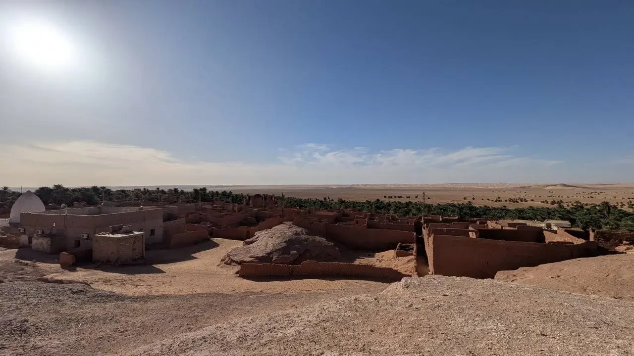 Strutture in terra e mura basse si stagliano nel vasto paesaggio desertico algerino.