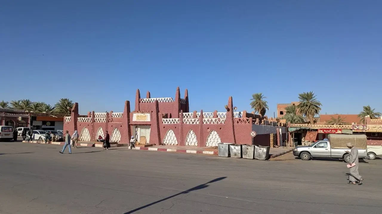 Vista di una città in Algeria con edifici in mattoni rossi sotto un cielo azzurro.