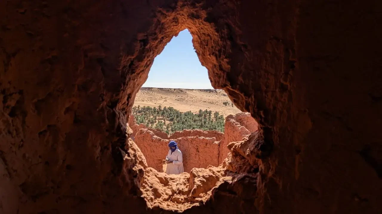 Una persona si trova all'interno di una grotta rocciosa con una vista aperta sul paesaggio esterno.
