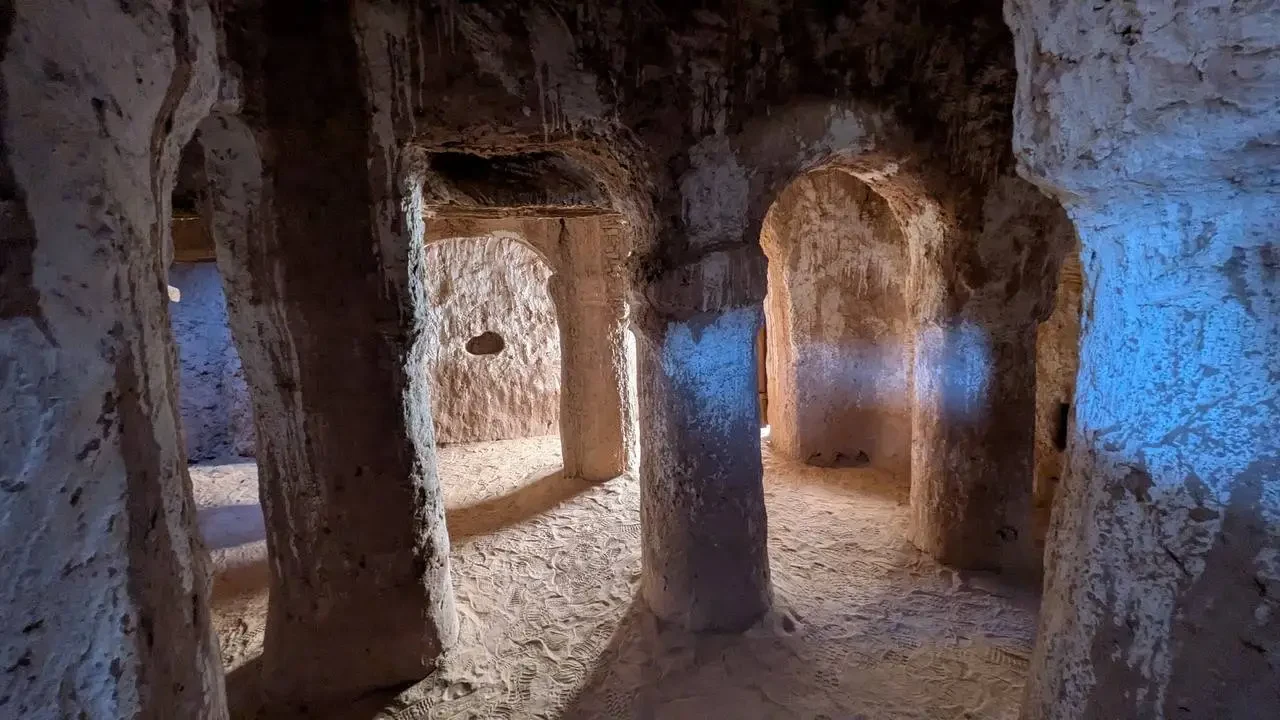 Interno di una moschea antica in pietra con archi e pareti intonacate.