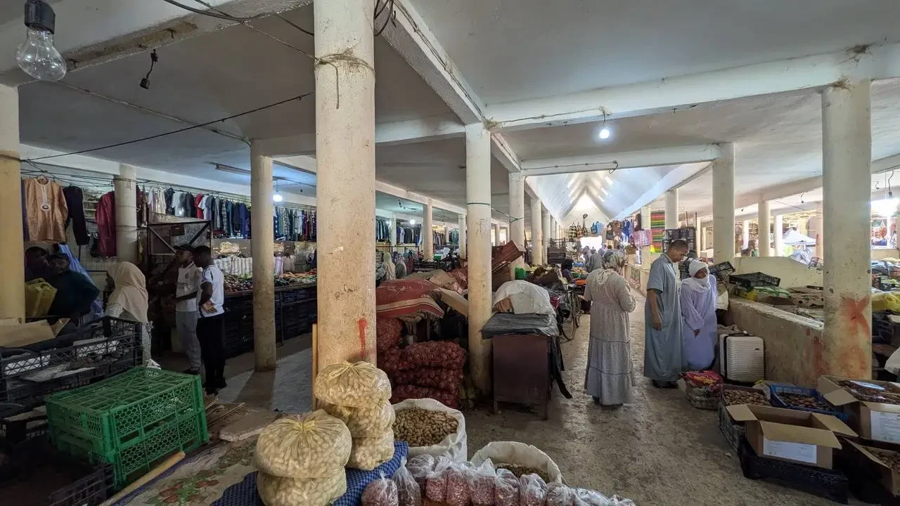 Un mercato coperto in Algeria mostra bancarelle di merci e persone che fanno acquisti.
