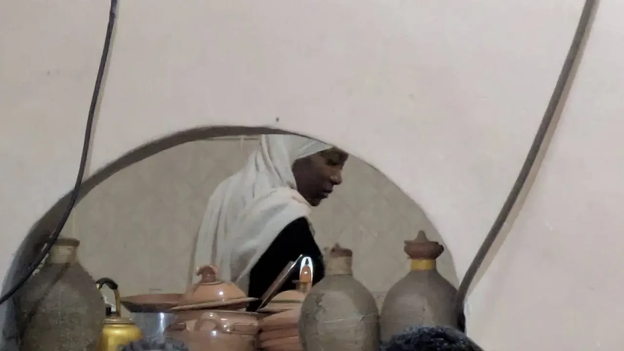 Una donna è circondata da vasi in terracotta in un ambiente interno in Algeria.