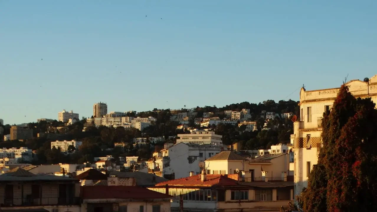 Una vista panoramica della città di Algeri con edifici sullo sfondo collinari.