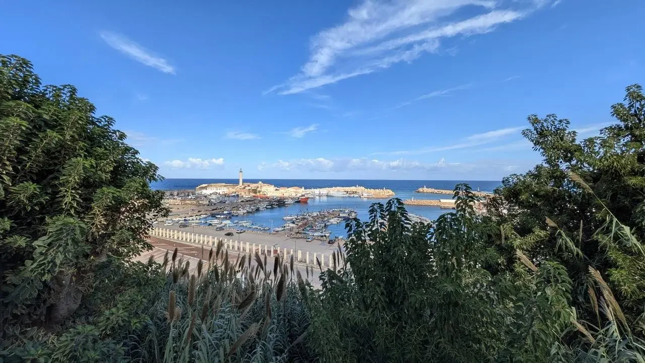 Vista della costa rocciosa e del mare sotto un cielo azzurro.