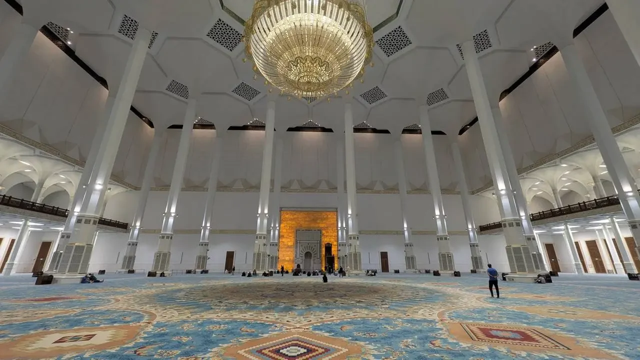 Interno sontuoso di un grande edificio storico algerino con soffitti a volta e lampadari imponenti.