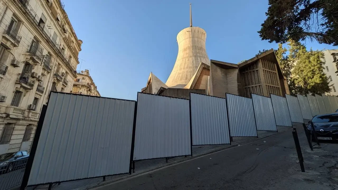 La facciata della Cattedrale di Sacré-Cœur ad Algeri è visibile in una fila di recinzioni metalliche.
