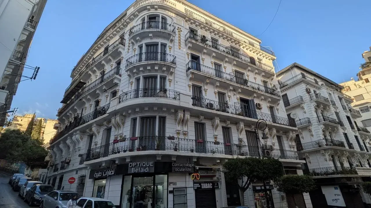 Un edificio storico in stile europeo con balconi si estende lungo una strada in Algeria.